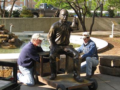 Artist David Iles and assistant Vincent Villarfanca install bronze sculpture of “Doc Silvey”