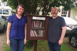 Amy Walton and James Garrett next to their Little Free Library, which they keep stocked with science books, classics and their favorite childrens' books-- in Spanish and English.