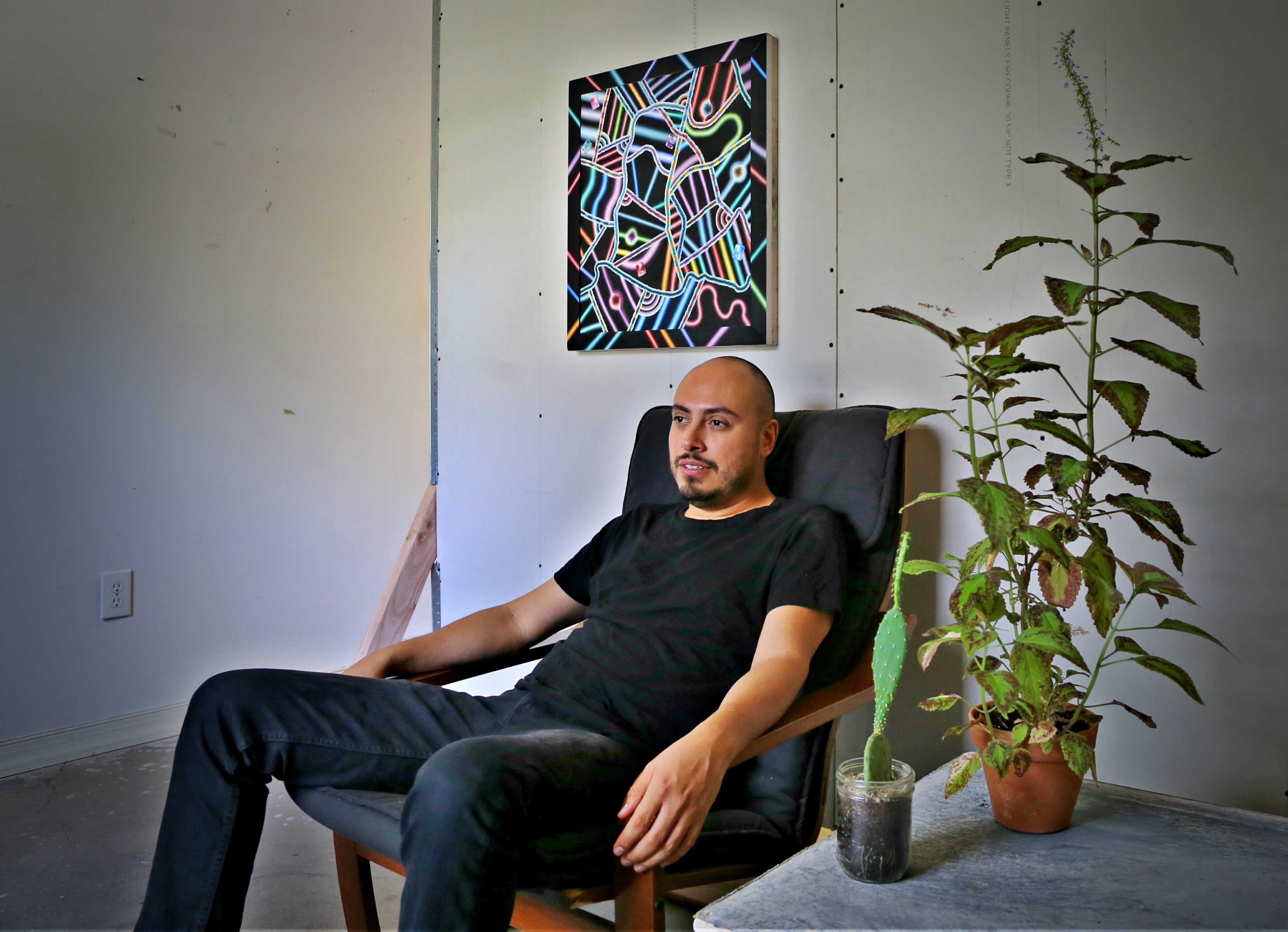 Arthur Peña sits in his studio. He says having plants in the room give him light and life. Photo: Hady Mawajdeh