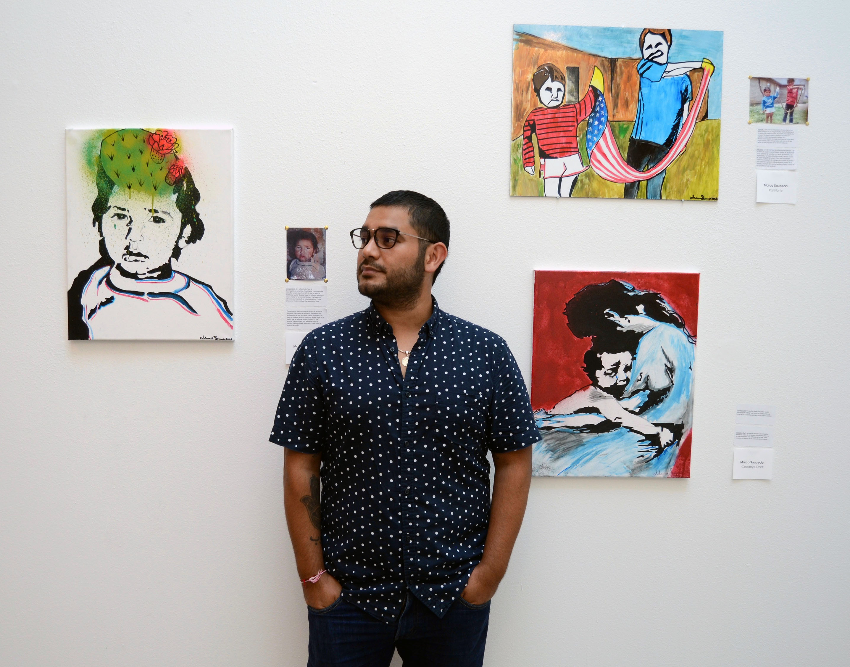 Marco Saucedo with three of his paintings: “De Nacimiento” (left), “Pal Norte” (upper right) and “Goodbye Dad” (lower right). Photo: Olivia Peregrino