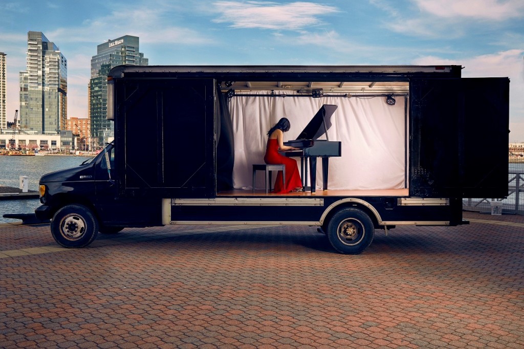 A photo of a woman playing a piano inside a truck