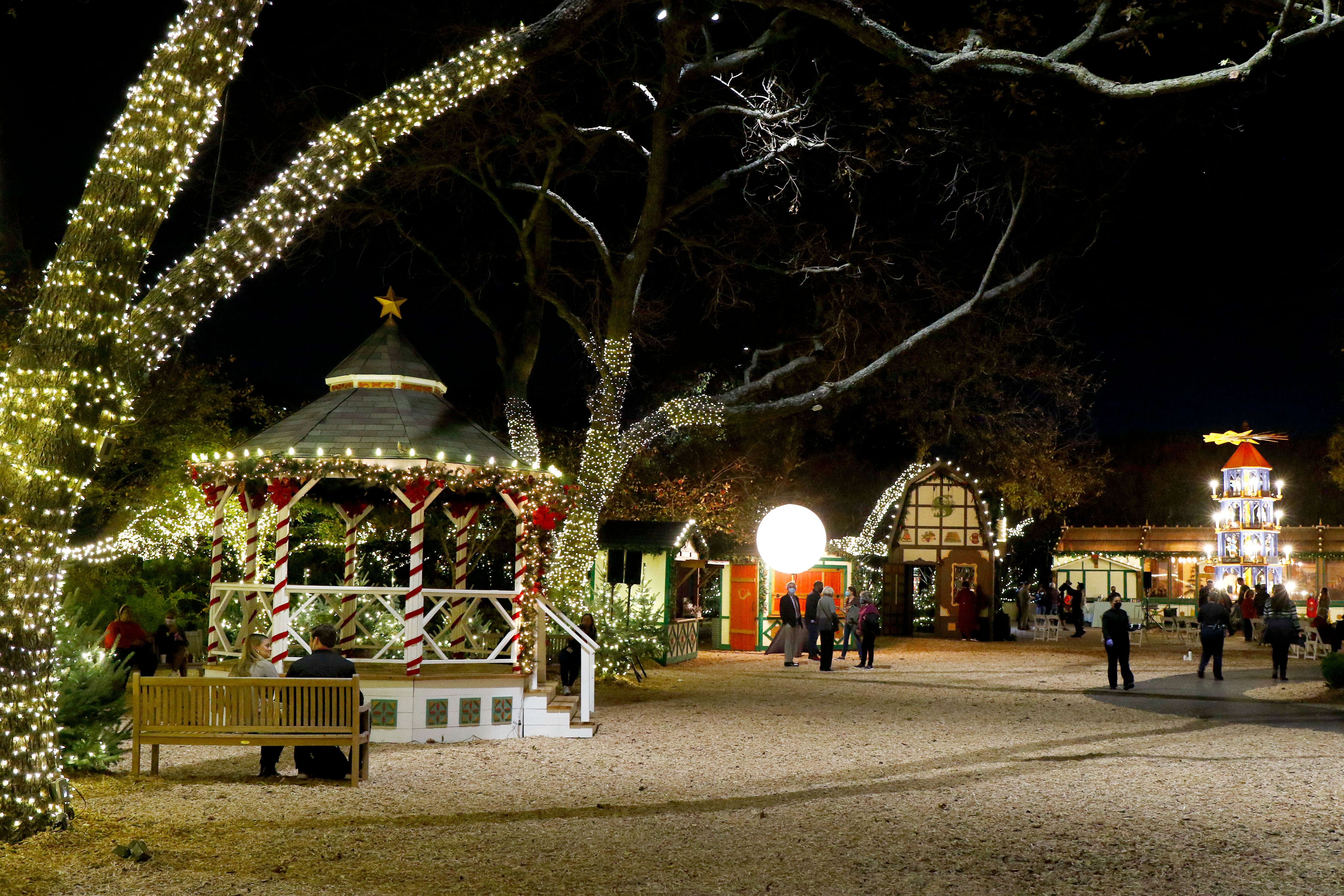 A nighttime view of Dallas Arboretum's Christmas Village. Holiday lights decorate European style buildings
