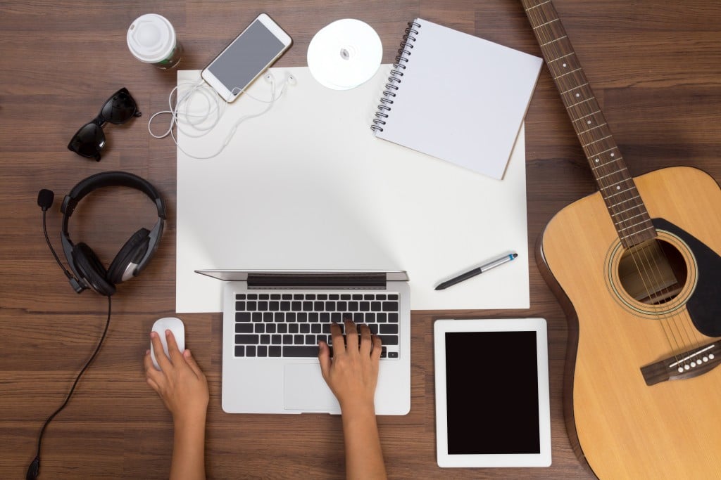 Office desk background, Hand using a laptop acoustic guitar and headphones recording scene project ideas concept, mobile phones, drawing equipment and cup of coffee. View from above with copy space