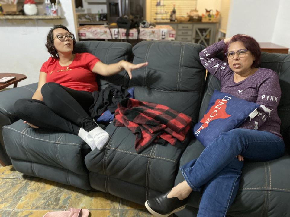 Two women talk on a couch. 